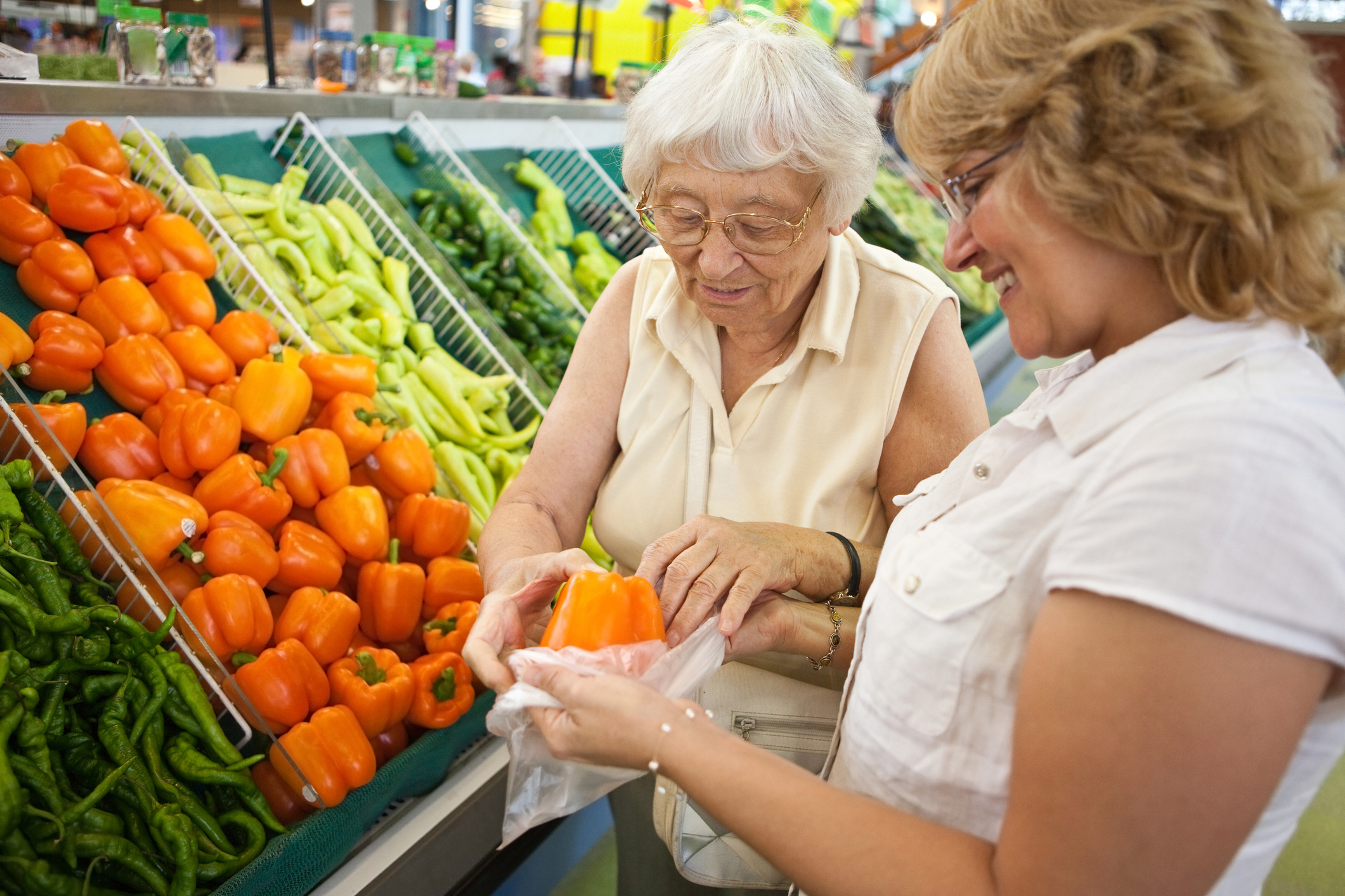 photo of elderly woman assisted by caretaker picking vegetables