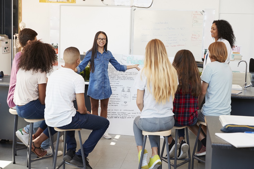 Photo of student presenting to peers with teacher