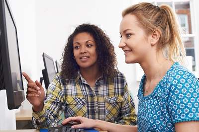 Photo of woman assisting young woman at a computer